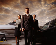 Three business people standing next to private jet, low angle view Photograph by Getty Images