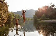 Young Couple Jumping Into River Photograph by Zave Smith