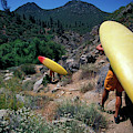 A Couple Carries Their Kayaks by Corey Rich A Couple Carries Their Kayaks by Corey Rich