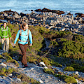 Two Women Hiking On An Ocean Trail by Lars Schneider Two Women Hiking On An Ocean Trail by Lars Schneider
