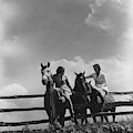 Two Women Sitting On A Fence With Horses
