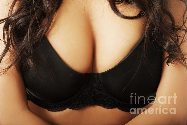 Beautiful realistic female breast in a black bra close-up isolated