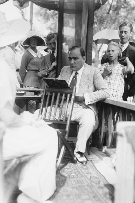 Enrico Caruso Leans back on chair holding a Board with Music Bath Sheet