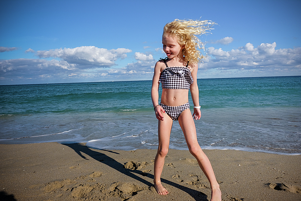 Girl Smiling Standing On The Beach Wind Blowing Hair Blue Skies Greeting  Card by Cavan Images