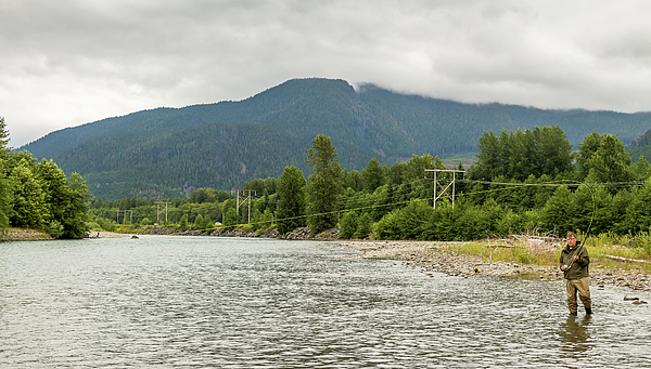 A fly fisherman hooked into a fish on the Kitimat River, in