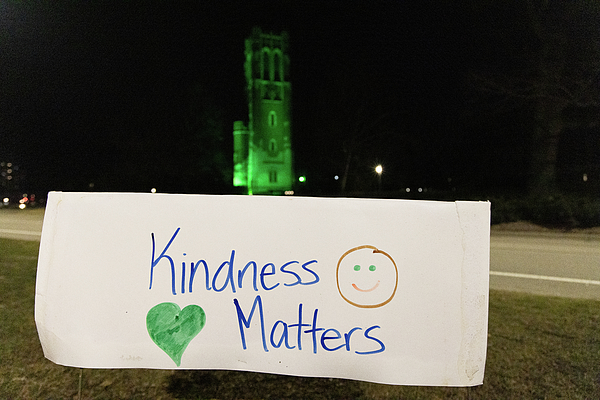 Kindness Matters sign in front of green lit Beaumont Tower at