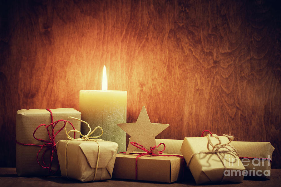 Christmas Photograph - Chistmas presents, gifts with a candle glowing on wooden wall background. #1 by Michal Bednarek