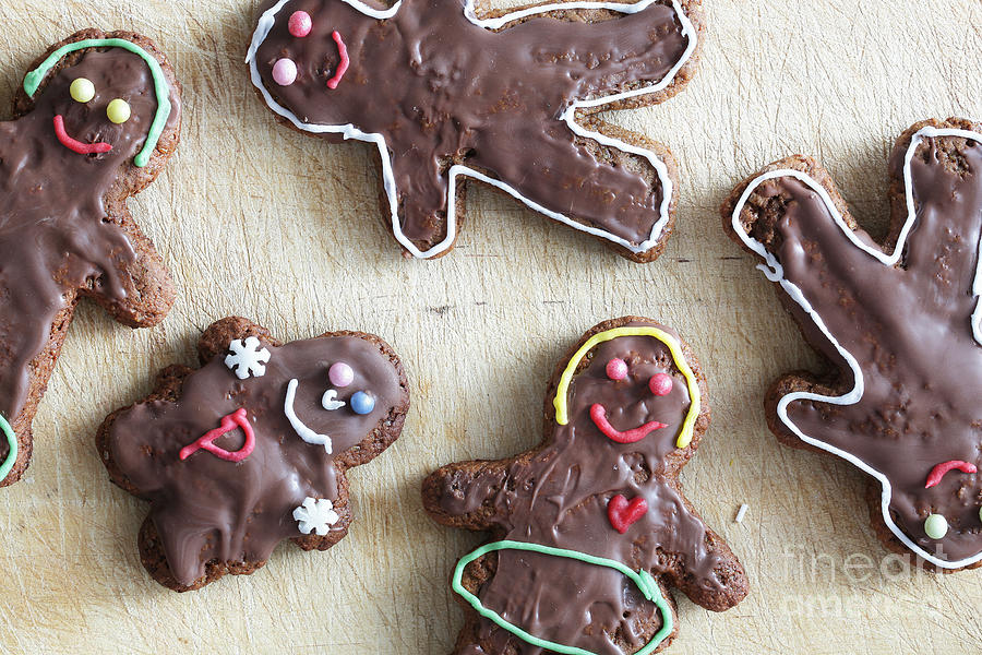 Christmas Photograph - Handmade decorated gingerbread people lying on wooden table #1 by Michal Bednarek