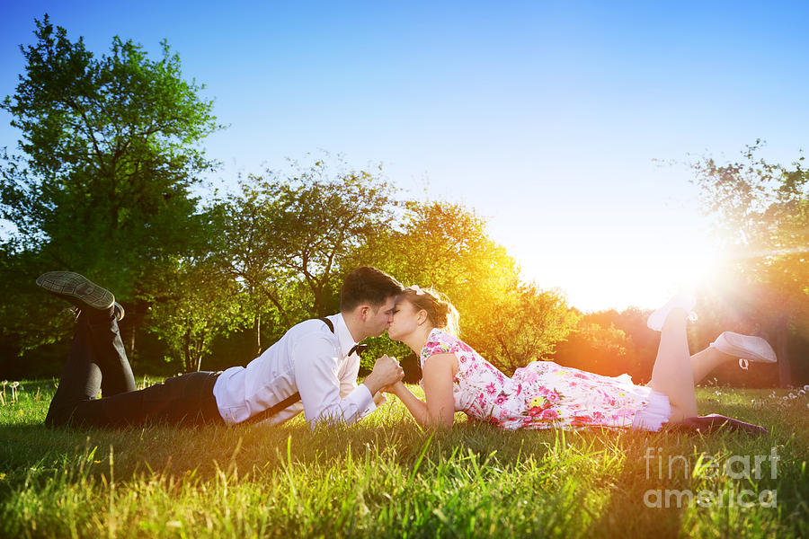 Romantic couple in love kissing while lying on grass #1 Photograph by Michal Bednarek