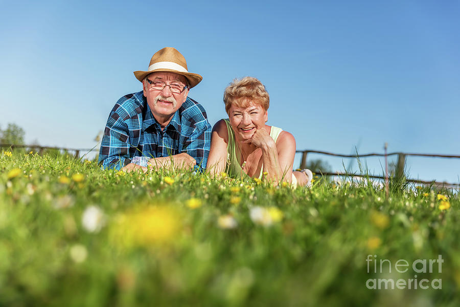 Senior couple lying on the summer field in green grass #1 Photograph by Michal Bednarek