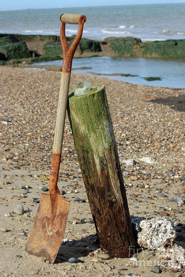Spade Leaning Against Breakwater On Beach Photograph