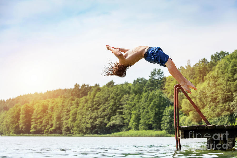 Young fit man jumping into a lake. #1 Photograph by Michal Bednarek