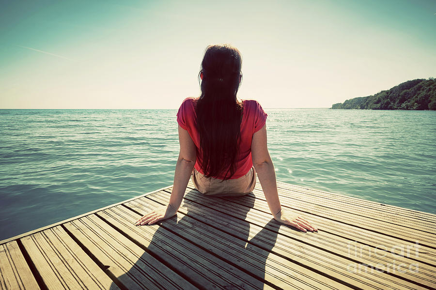 Young woman resting on jetty looking at the calm sea on sunny summer day. #1 Photograph by Michal Bednarek