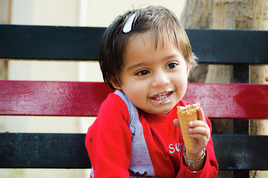 Little Girl Sitting On A Bench And Eating An Ice-Cream Cone Photograph ...