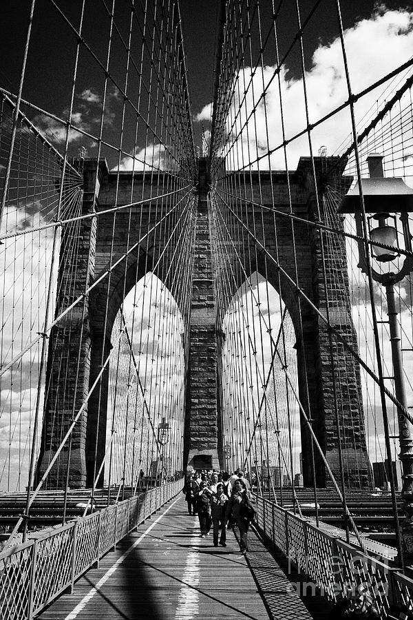 people walking over the brooklyn bridge between cables New York City ...