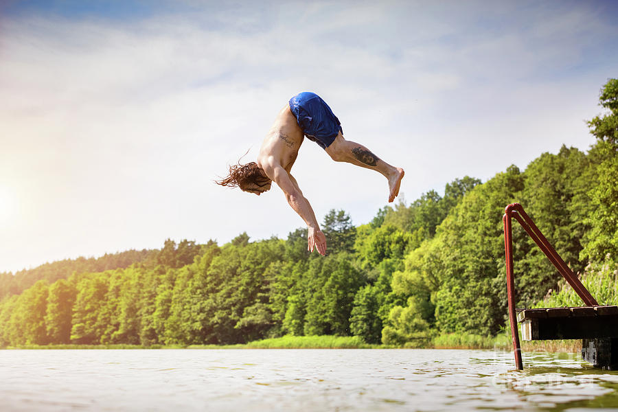 Young fit man jumping into a lake #3 Photograph by Michal Bednarek