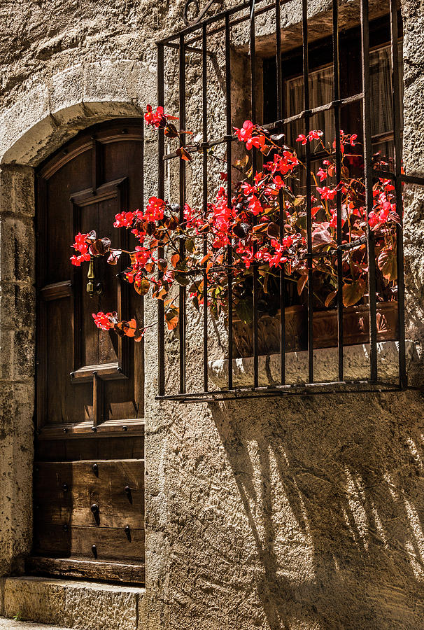 A barred window and door  With a Red Begonia and contrasty shadows Saint Paul De Vence France Photograph by Maggie Mccall