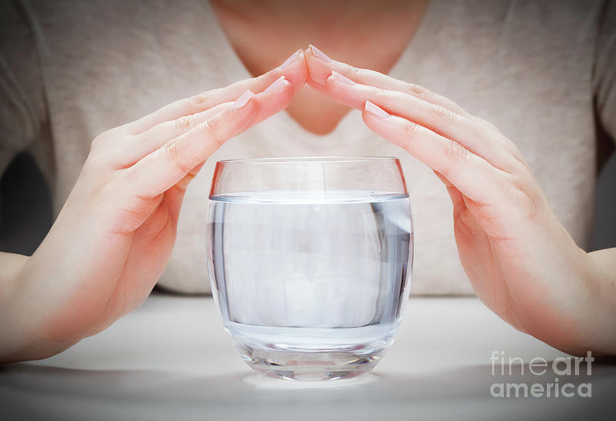 A glass of clean mineral water covered by womans hands. Environment protection Photograph by Michal Bednarek