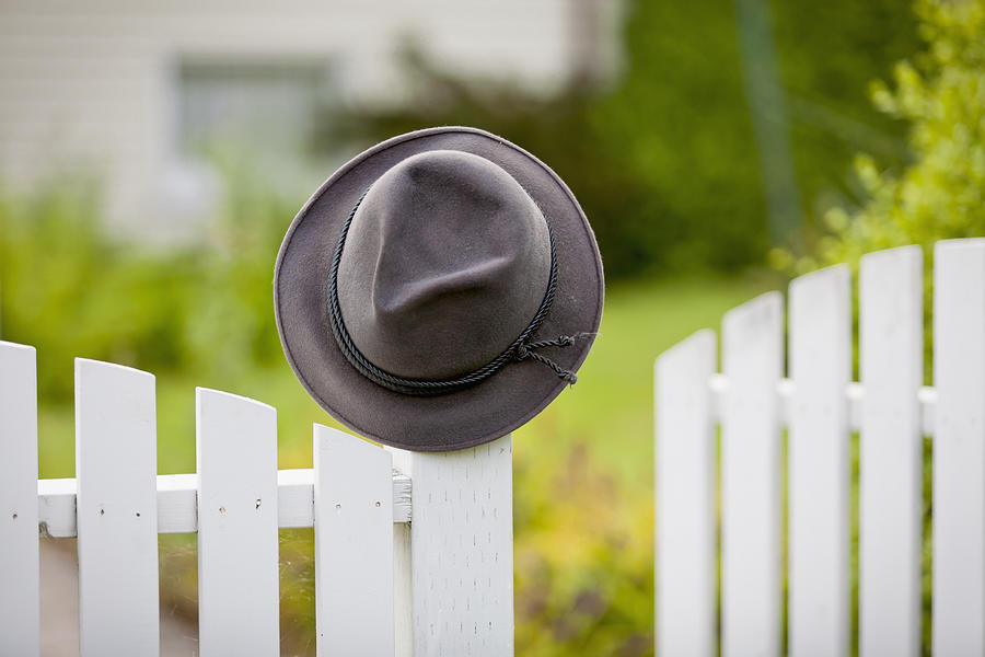 Hat Photograph - A Hat Hanging On The Post Of A White by Lorna Rande