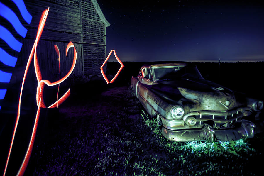 A light painted scene of a rusty caddy by a barn and cornfield Photograph by Sven Brogren