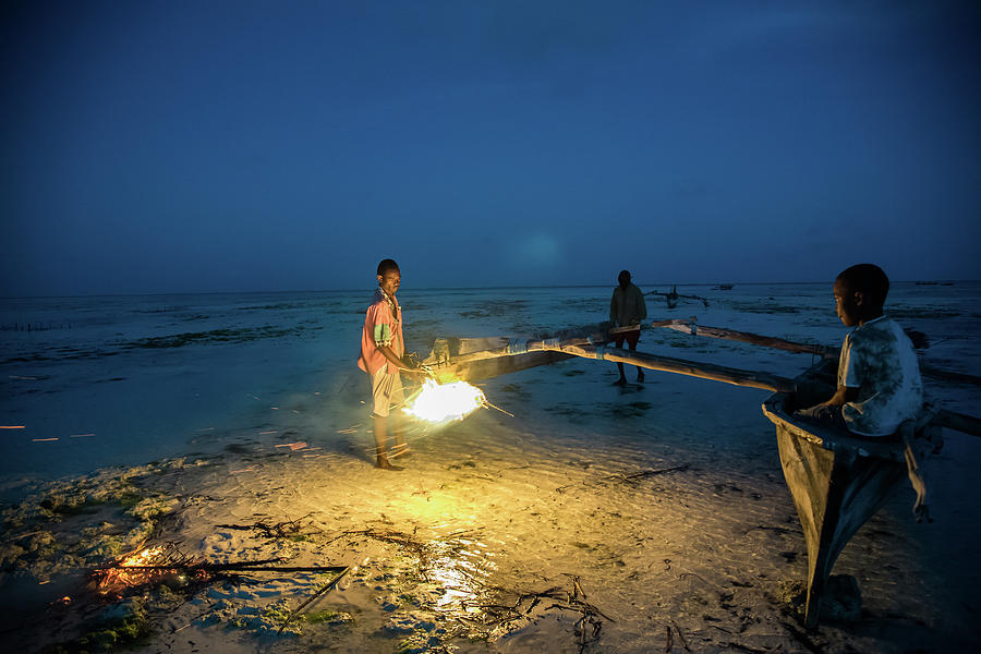 A local fisherman uses flame to repair his boat at sunset by Gareth Pickering A local fisherman uses flame to repair his boat at sunset by Gareth Pickering
