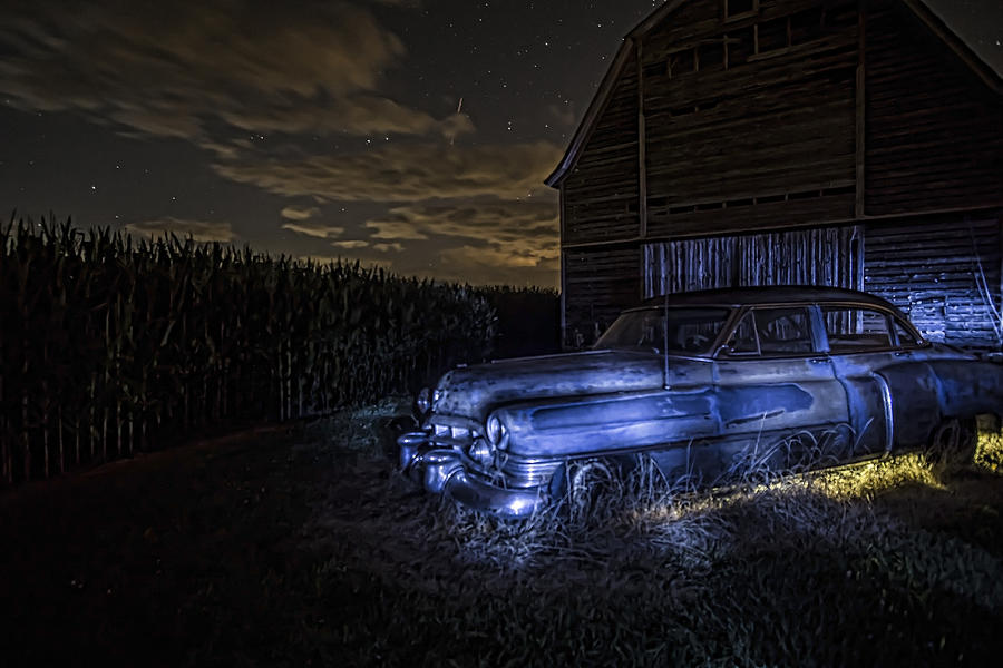 A rusty 50s Cadillac in painted blue and yellow light one starry night Photograph by Sven Brogren