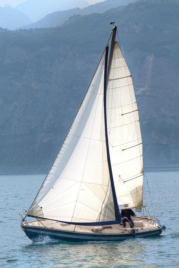 A sailing boat is sailing over the Lake Garda Photograph by Gina Koch