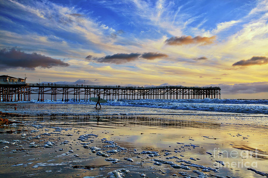 A surfer heads home under a cloudy sunset at Crystal Pier Photograph by Sam Antonio