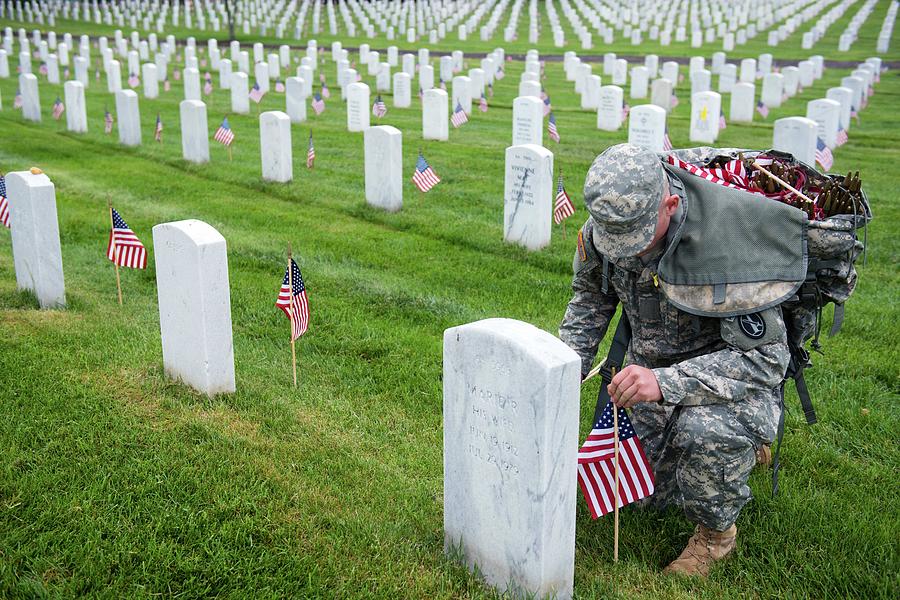 A U.S. Army Soldier places American flags at headstones in Section 64 ...