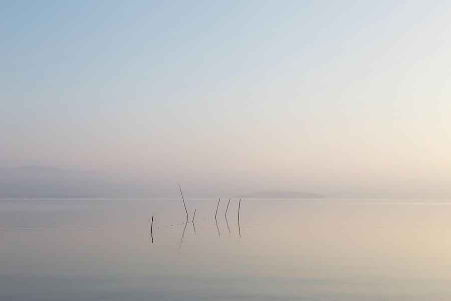 Nature Photograph - A very minimalistic view of a lake at dawn, with soft light, war by Massimo Discepoli