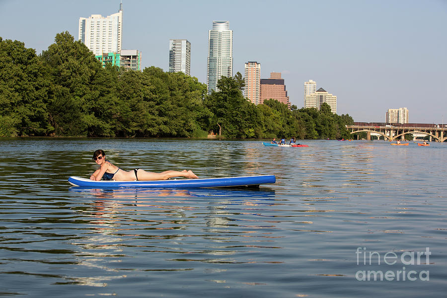 Sup Photograph - A woman having a great time sunning on a stand up paddle boarding, SUP on Lake Austin with the Austin Skyline in the background - Stock Image by Dan Herron