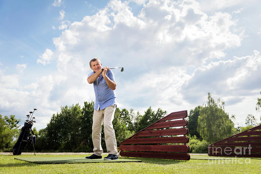 Active senior man hitting a golf ball. Photograph by Michal Bednarek