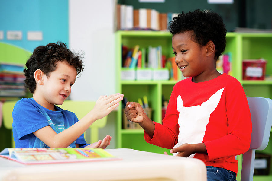 African boy and american boy play togather in library Photograph by Anek Suwannaphoom