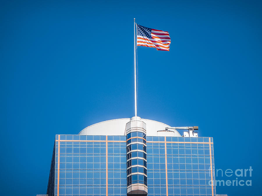 American flag waving on top of a modern skyscraper Photograph by JR Photography