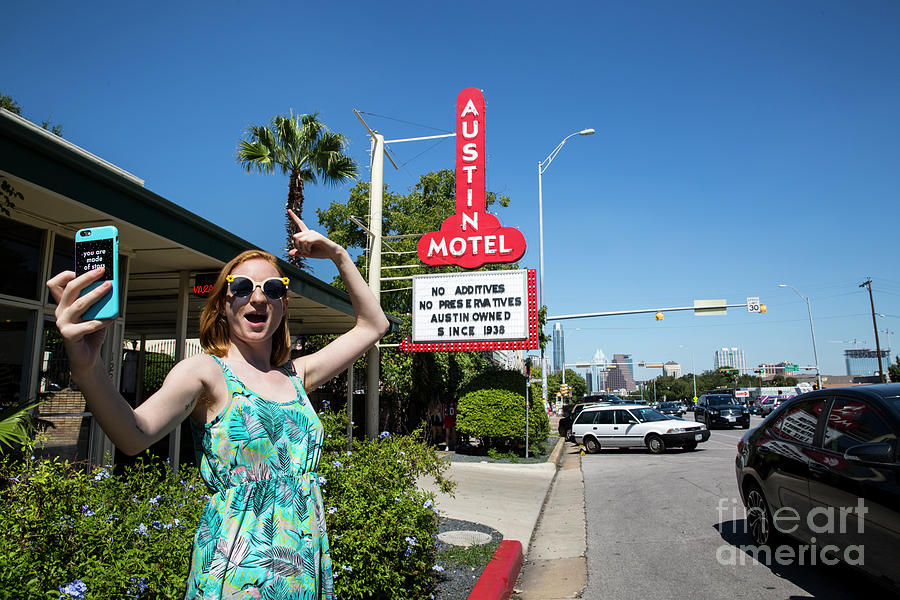 Austin Photograph - An Austin local takes a selfie in front of the famous Austin Motel Sign in South Congress, Austins most eclectic and most popular spots for live music, dining, and unique shopping by Dan Herron