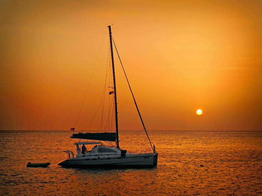 Anchored sailboat at sunset Photograph by Carolyn Derstine