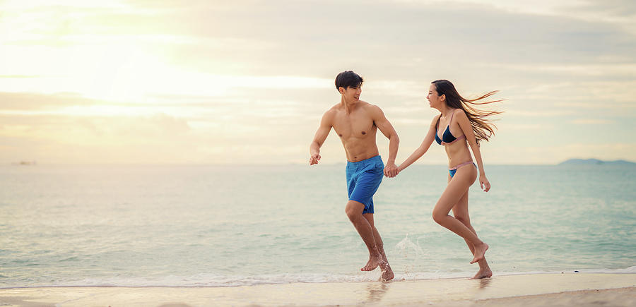 Asian couple run togather on the beach  Photograph by Anek Suwannaphoom