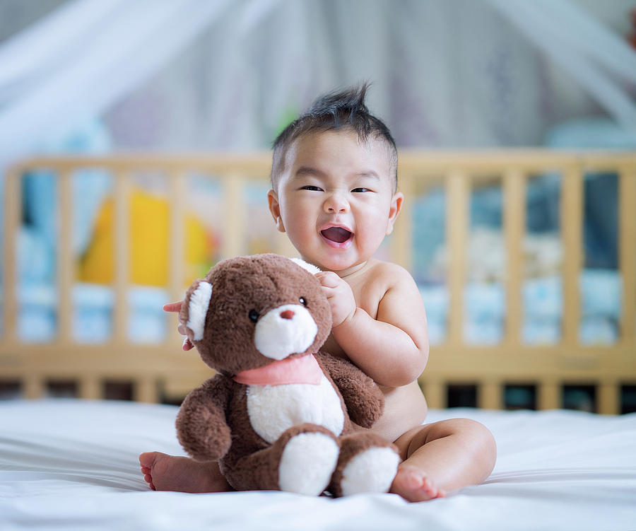 Asian new born baby sit and hug a teddy bear  Photograph by Anek Suwannaphoom