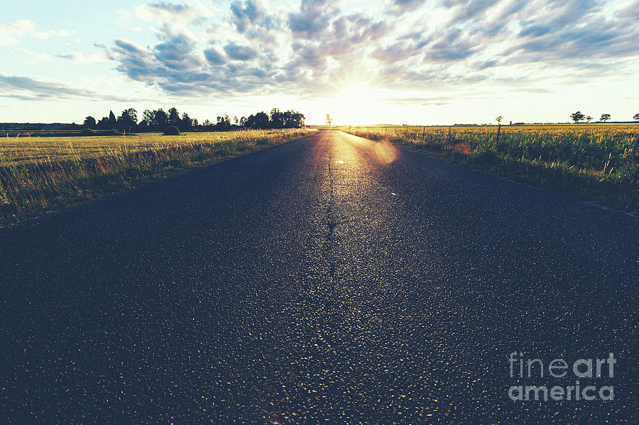 Asphalt country road, a grass field and sunset. Photograph by Michal Bednarek