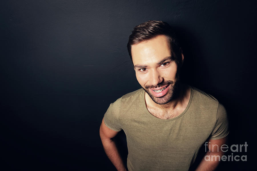 Attractive, smiling man standing next to a wall. Photograph by Michal Bednarek