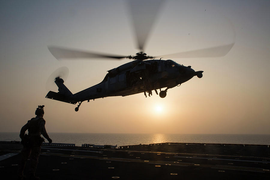 A US Navy SH60 Sea Hawk Helicopter hovers the amphibious assault ship USS Bataan LHD 5 Photograph by Paul Fearn