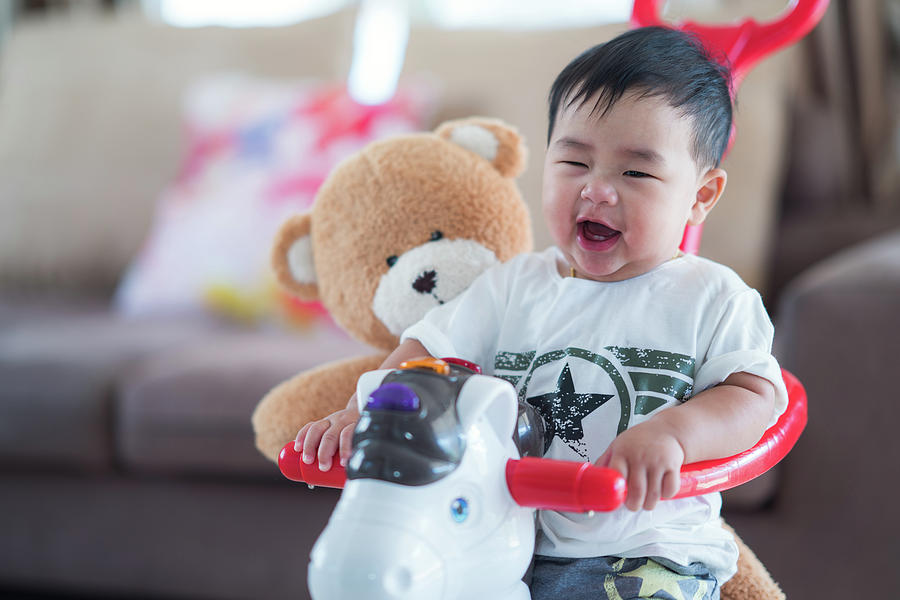 Baby and teddy bear play a bycycle toy Photograph by Anek Suwannaphoom