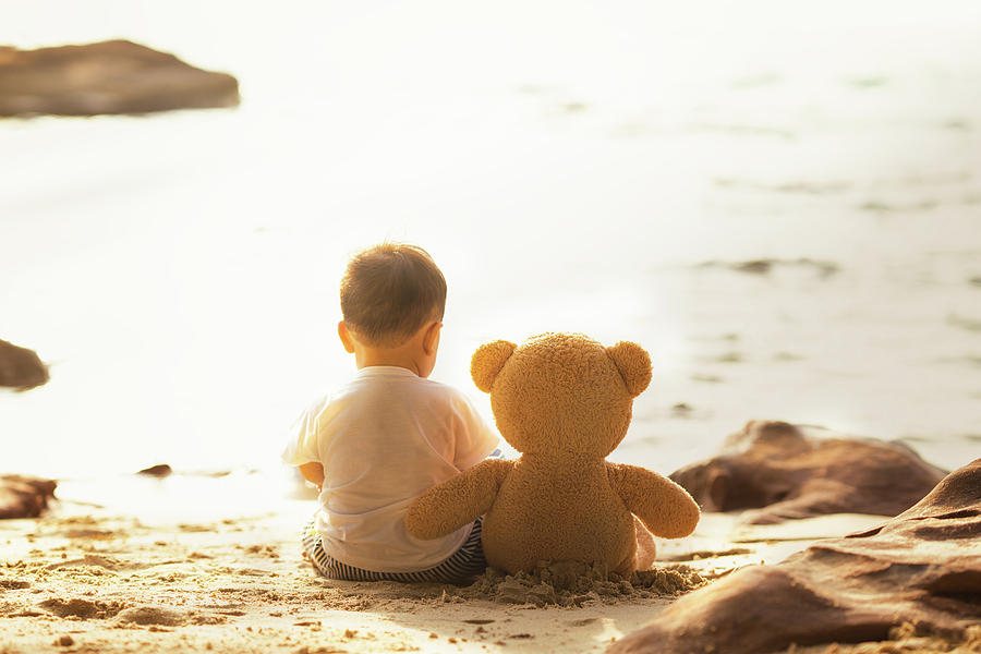 Baby and teddy bear sit togather on the beach Photograph by Anek Suwannaphoom