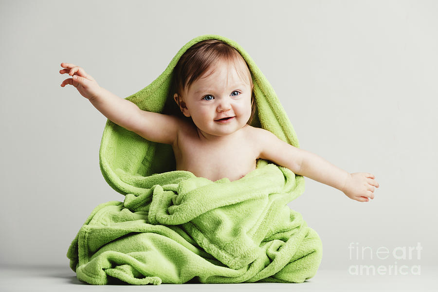 Baby covered in green blanket in a funny pose. Photograph by Michal Bednarek