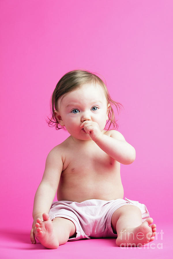 Baby girl putting her hand into her mouth. Photograph by Michal Bednarek