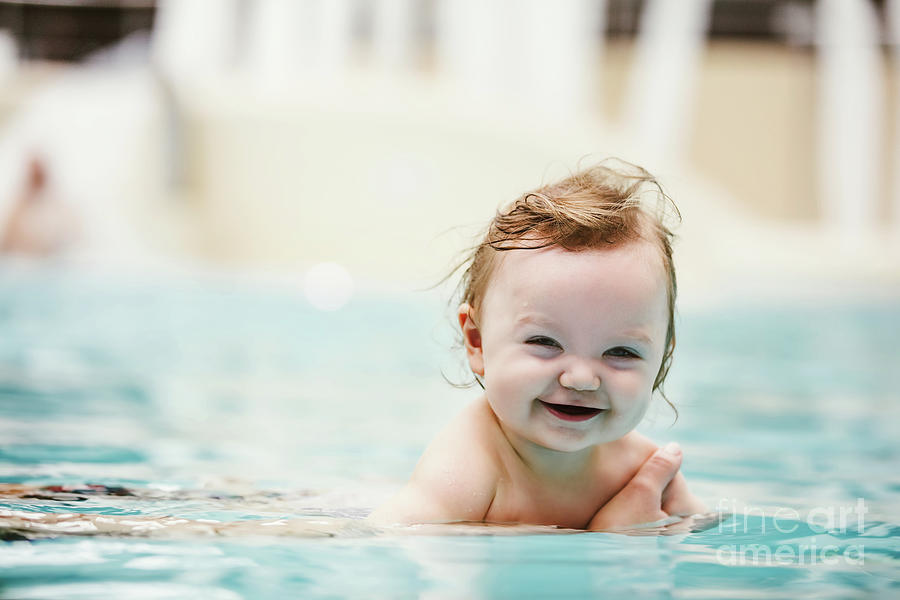 Baby girl smiling and swimming in water. Photograph by Michal Bednarek
