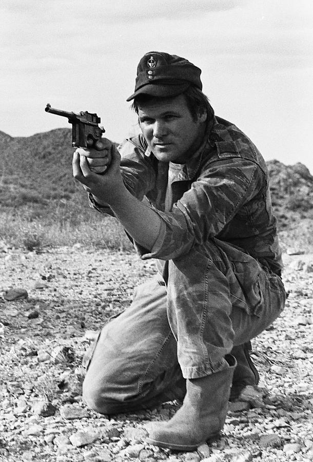 Barry Sadler crouching with one of his favorite pistols Tucson Arizona 1971 Photograph by David Lee Guss