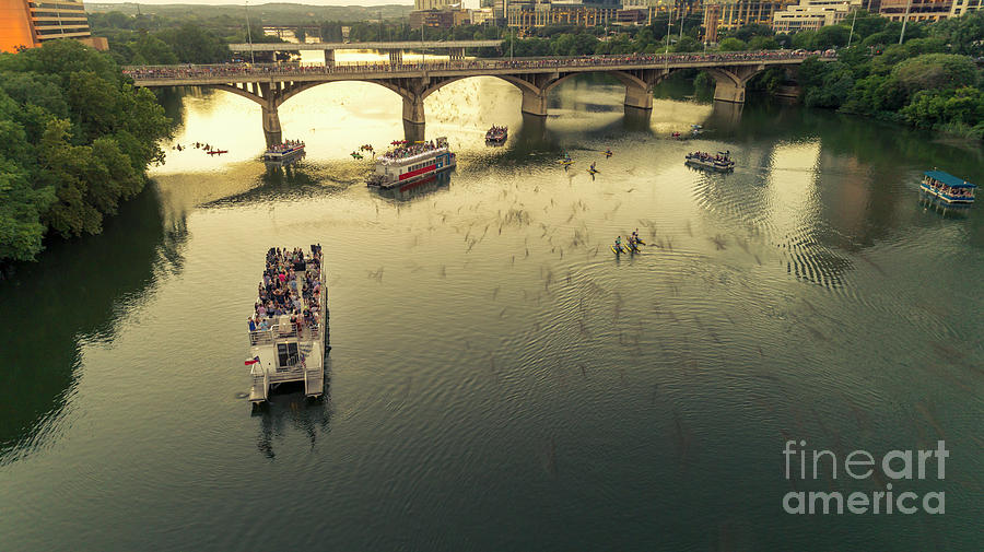 Bat watchers stand in tour boats as the bats take flight during sunset