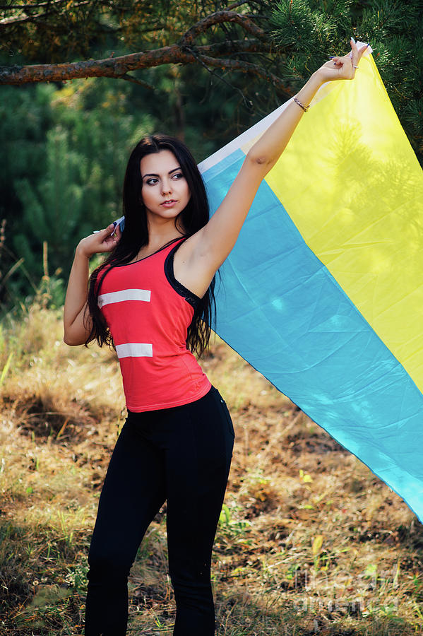 Beautiful brunette model posing in a park with flag of Ukraine ...
