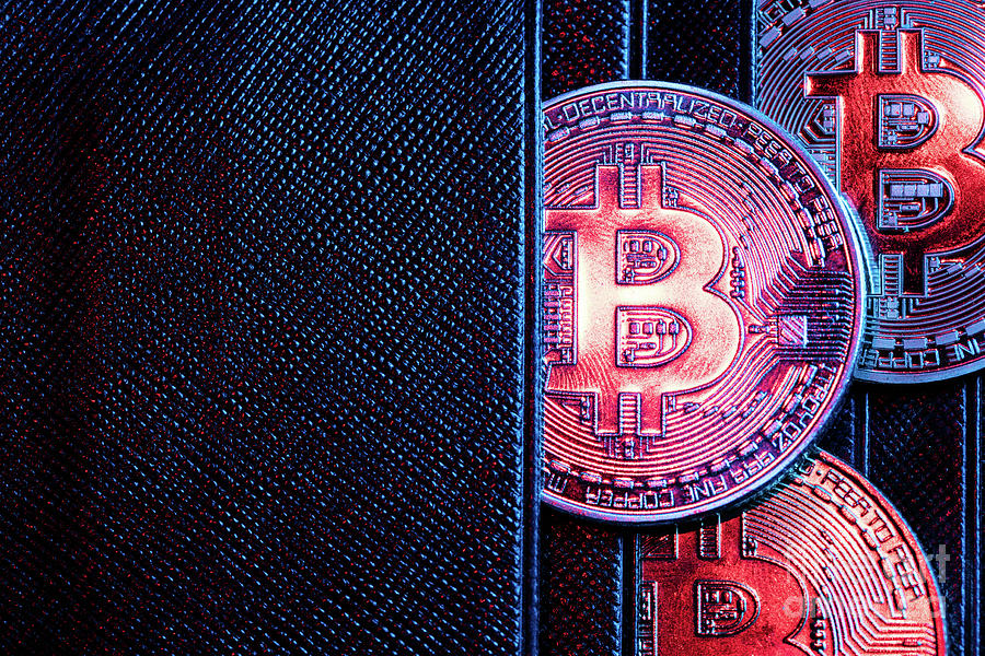 Bitcoin coins sticking out of a wallet. Photograph by Michal Bednarek
